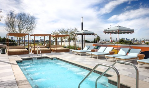 A pool with a metal ladder and a row of sun loungers.
