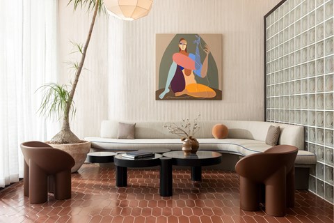 A living room with a white sofa, a brown chair, a coffee table, and a painting on the wall.