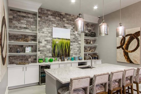 A kitchen with a white countertop and a stone wall.