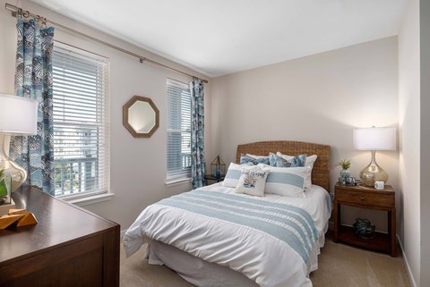 A bedroom with a bed, nightstand, and window with curtains.