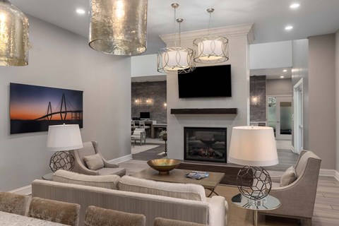 A modern living room with a fireplace and a painting of a sunset.