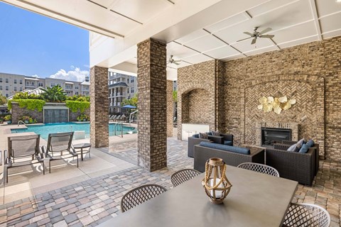 A patio with a table and chairs and a pool in the background.