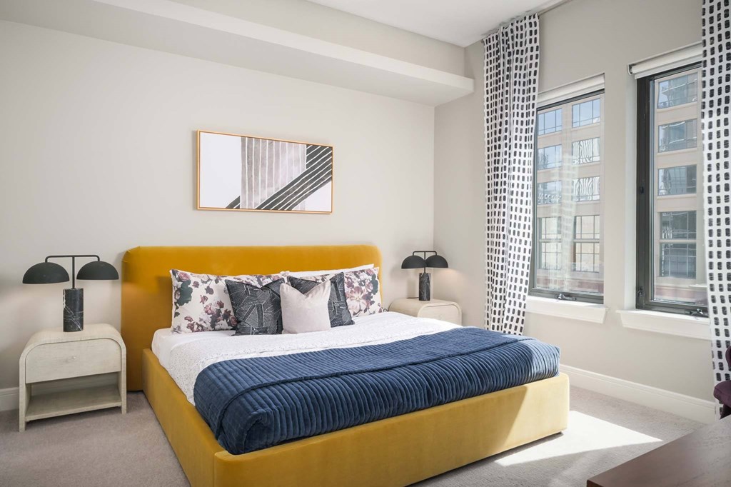 A bedroom with a yellow bed and a painting on the wall.