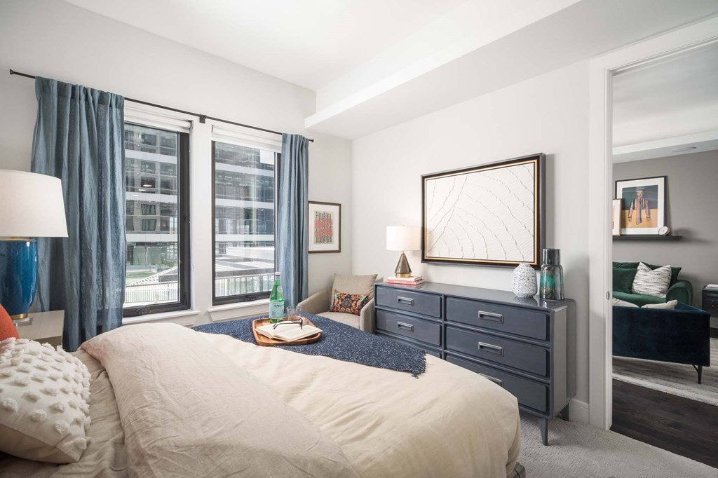 A bedroom with a large bed, a dresser, and a mirror.