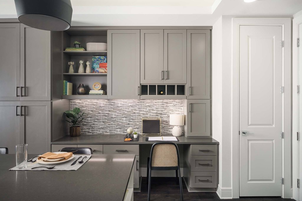 A modern kitchen with a grey countertop and a stone backsplash.