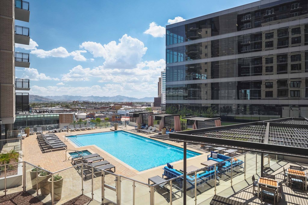 A swimming pool surrounded by lounge chairs and buildings.