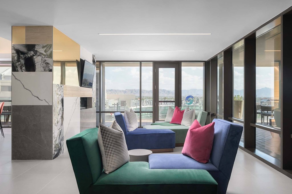 A modern living room with a green sofa and a large window overlooking the mountains.
