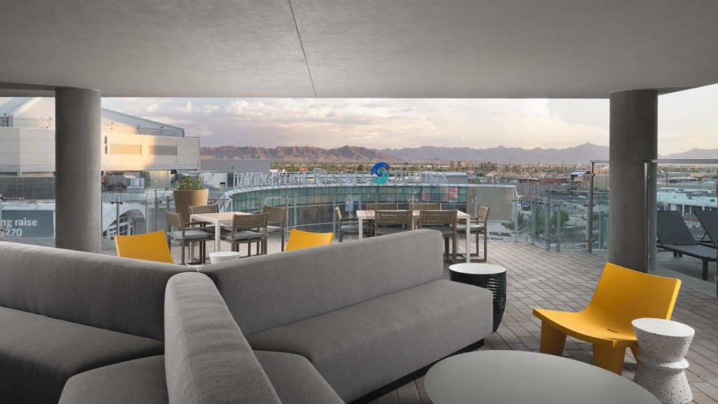 A grey couch is in the foreground of a room with a view of the mountains.