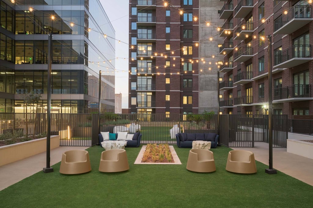 A modern outdoor seating area with a grassy lawn and four beige chairs.