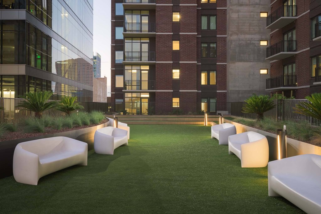 A modern courtyard with white couches and a grassy area.