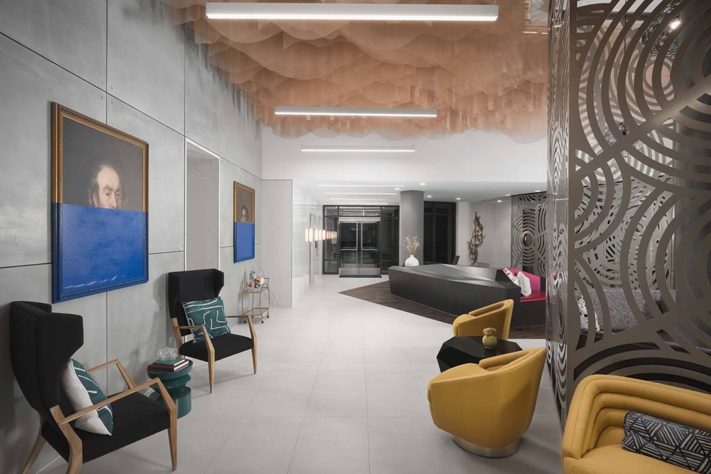 A modern living room with a large abstract painting on the wall and a variety of colorful chairs.