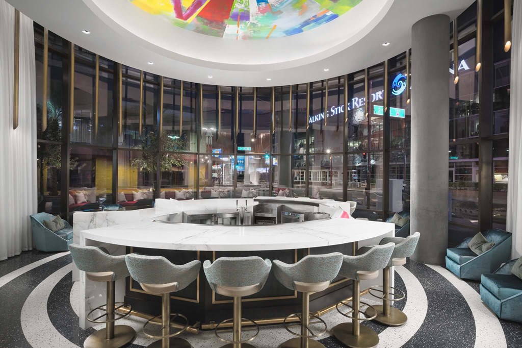 A round table with chairs is in the middle of a room with a large circular window.