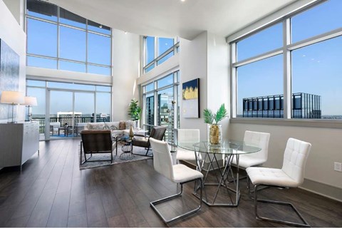 A modern dining room with a glass table and white chairs.
