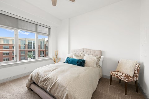 A bedroom with a large bed and a chair.