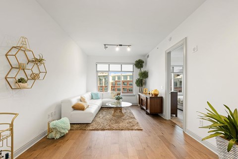 A living room with a white couch and a wooden floor.