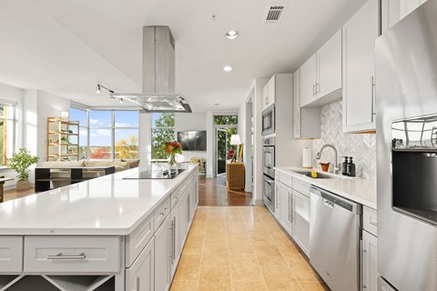 A modern kitchen with a long counter and stainless steel appliances.