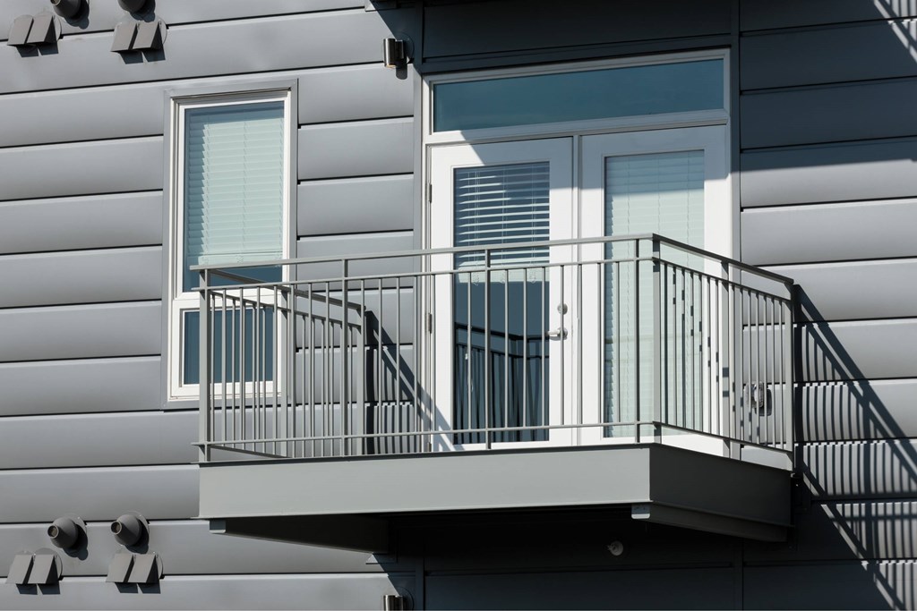 A balcony with a metal railing and a window with blinds.