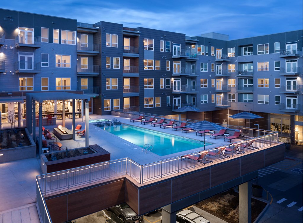 A large apartment complex with a pool and a lit patio area.