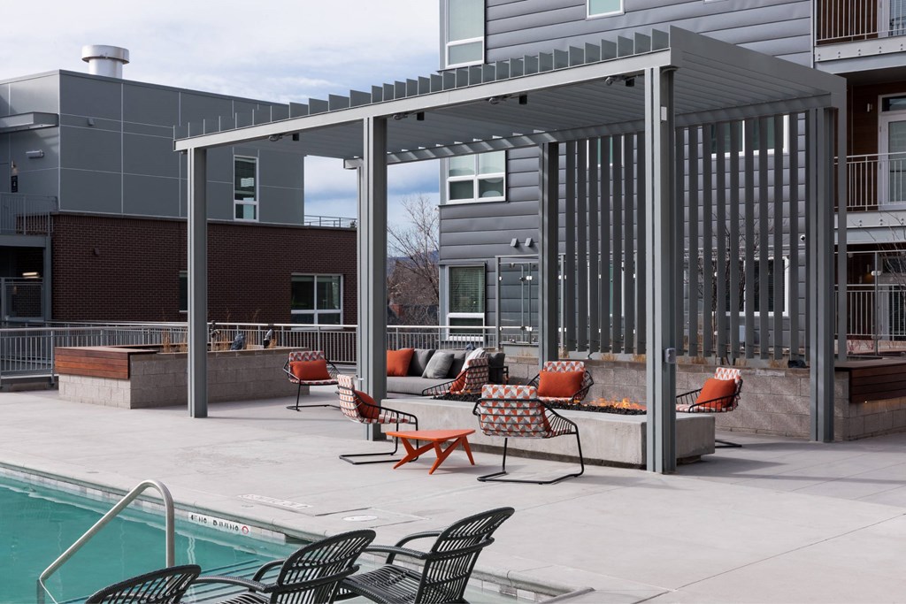 A pool area with a black metal patio umbrella and chairs.