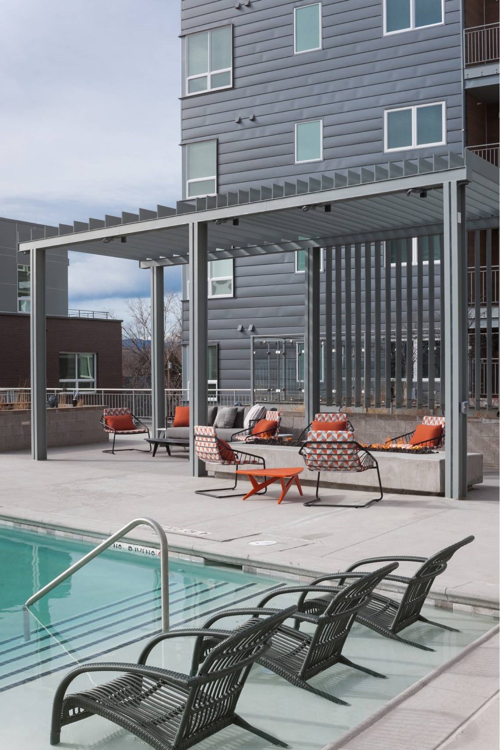 A pool area with chairs and a building in the background.