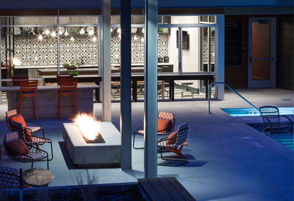 A patio with a fire pit and chairs.