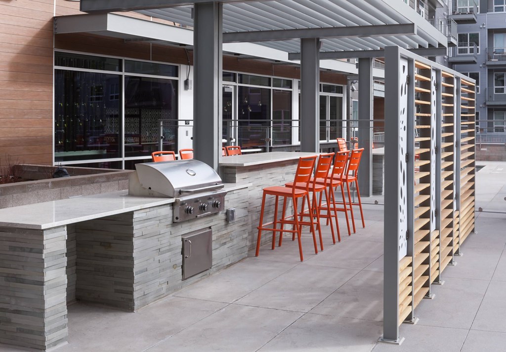 A patio with a grill and chairs.