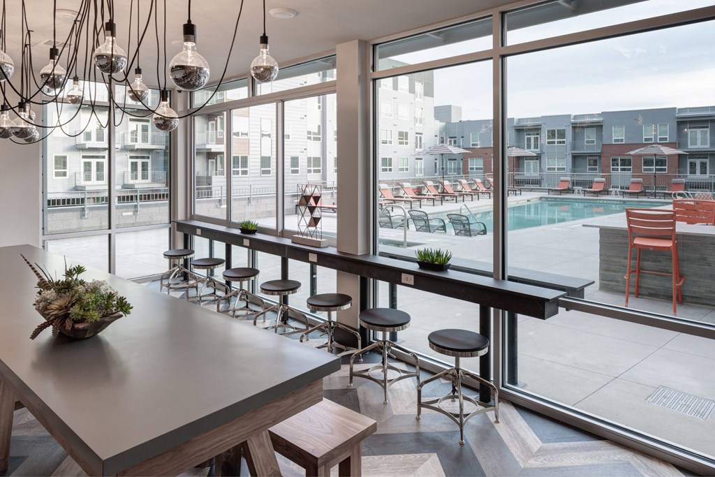A modern kitchen with a long counter and a view of a pool and buildings outside.