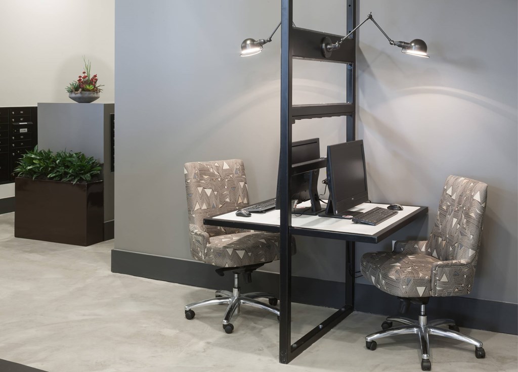 A modern office space with a desk, chairs, and a plant.