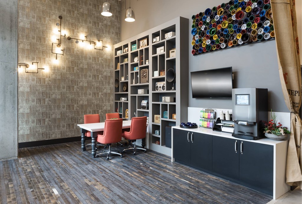 A room with a brick wall, a table with chairs, and a shelf with various items.