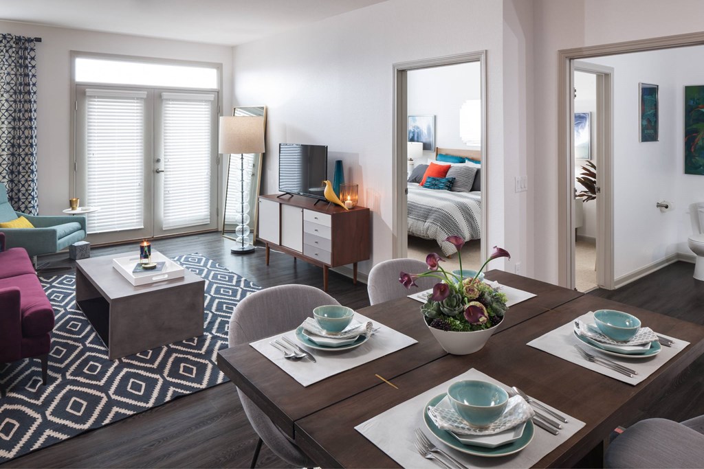 A modern dining room with a wooden table set for two.