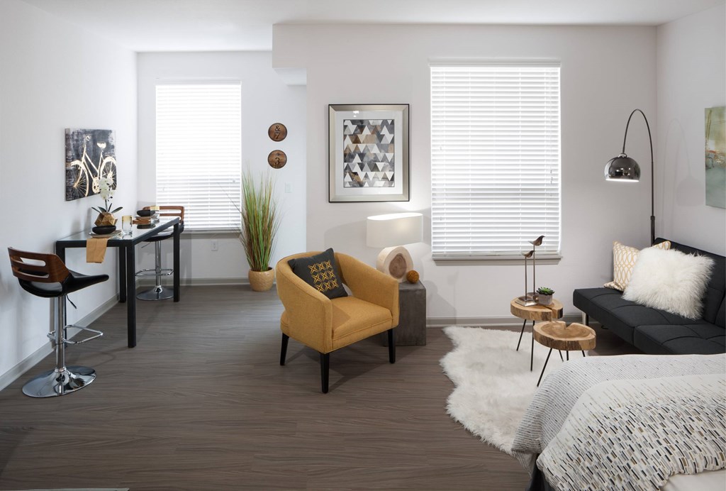A modern living room with a yellow armchair and a black couch.