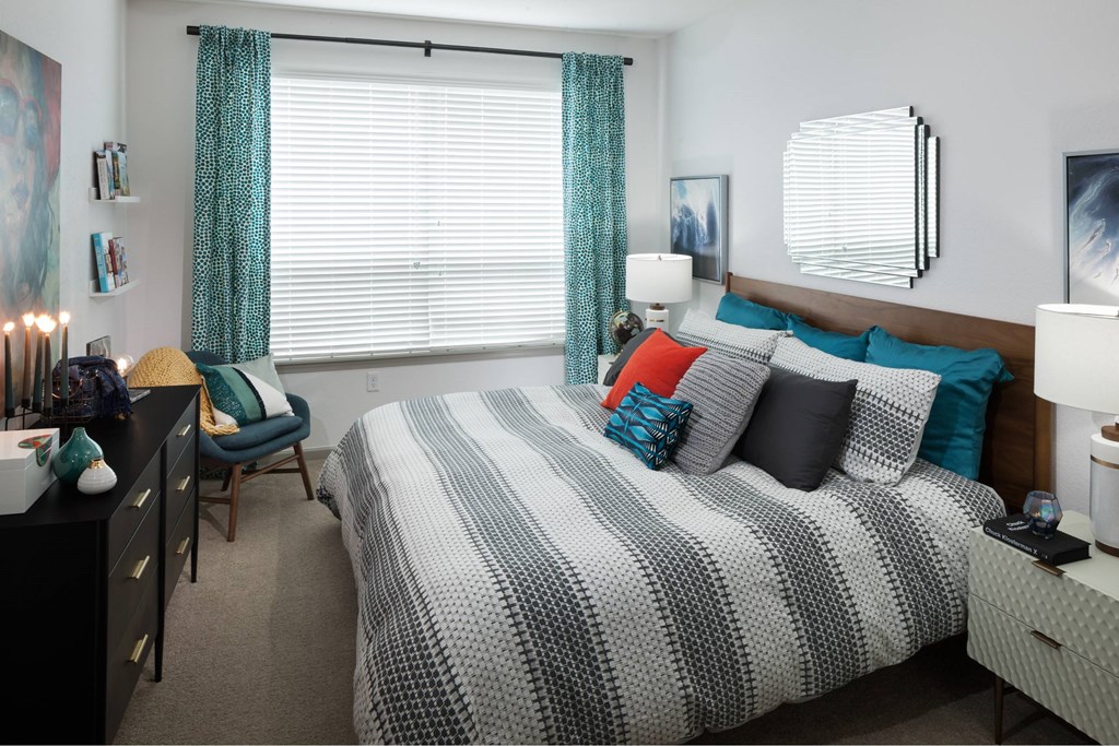 A bedroom with a bed, chair, and a nightstand.