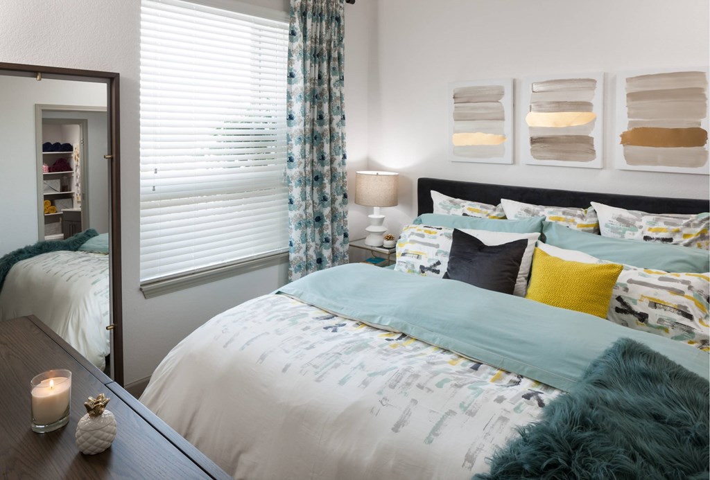 A bedroom with a large bed and a nightstand with a candle on it.