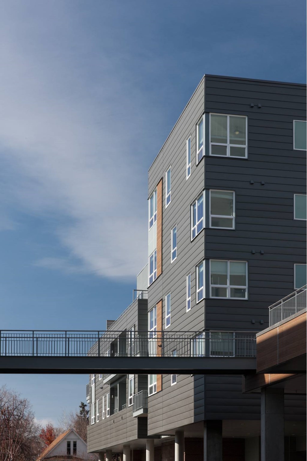 A modern building with a balcony and a bridge connecting it to another building.