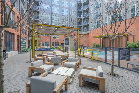A patio with wooden furniture and a pool in the background.