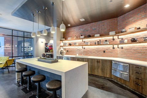 A modern kitchen with a white counter and black stools.