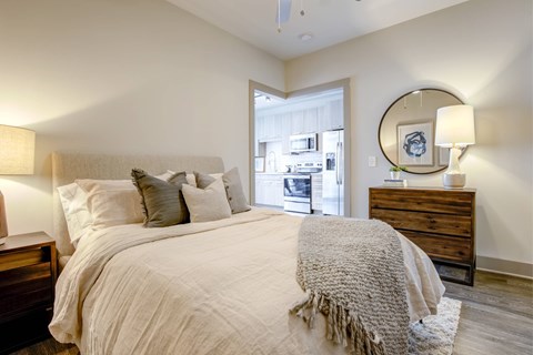 A bedroom with a large bed, a dresser, and a mirror.