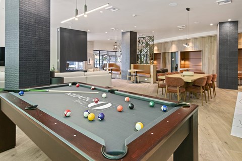A pool table is in the middle of a room with a dining table and chairs.