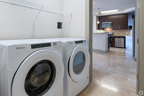 Two white front load washing machines in a laundry room.