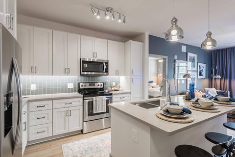 A modern kitchen with white cabinets and a stainless steel refrigerator.