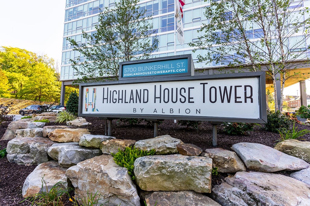 A sign for Highland House Tower by Albion stands in front of a building.
