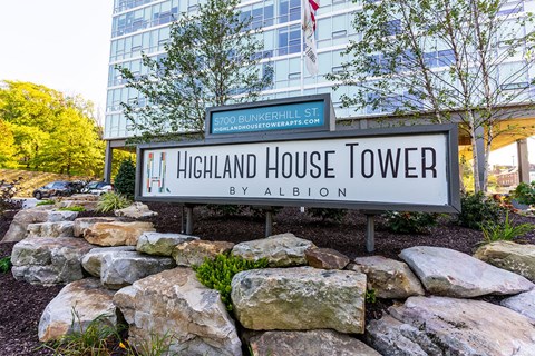 A sign for Highland House Tower by Albion stands in front of a building.