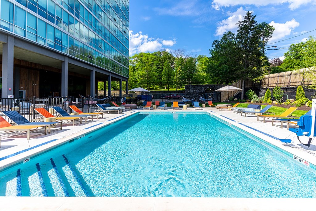 A large swimming pool with lounge chairs and a building in the background.