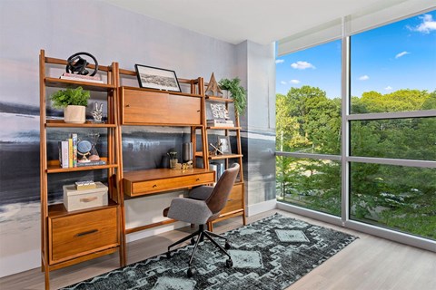 A room with a desk, chair, and shelves with various items.