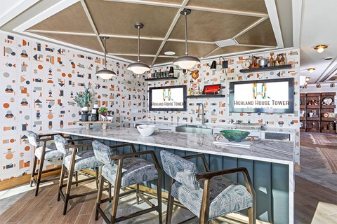 A bar area with a counter and chairs with a sign that says Highland House Tower.