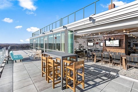 A rooftop patio with wooden chairs and tables.