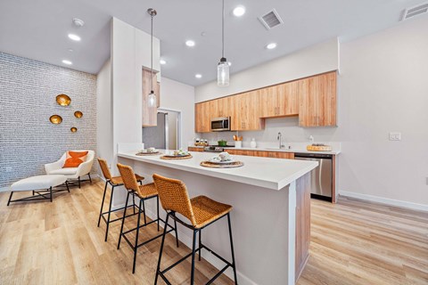 A kitchen with a white counter and orange chairs.