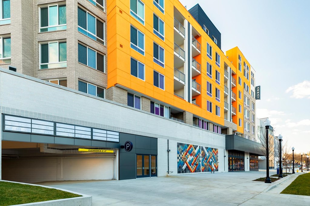 A modern building with a parking garage in front.