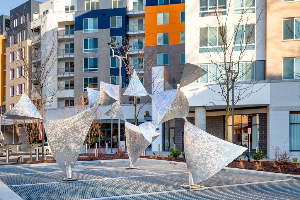 A group of white sculptures are in the foreground of a city street.