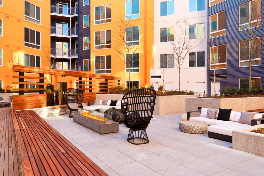 A patio with a black chair and a fire pit.